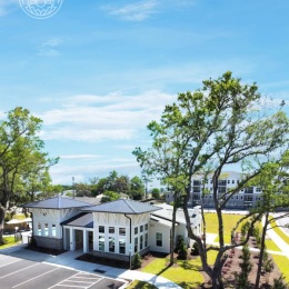 a spacious waterfront building on a lawn of trees
